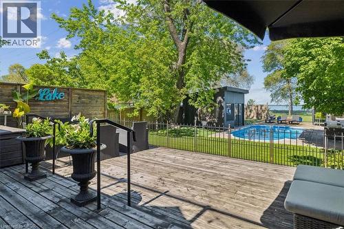 Expansive wood deck overlooking a fenced in-ground pool, a detached pool house, and a prominent body of water - 573 Beach Boulevard, Hamilton, ON - Outdoor With In Ground Pool With Deck Patio Veranda With Exterior