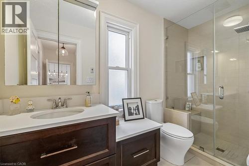 Bathroom featuring a glass-enclosed shower with a rainfall showerhead, a dark wood-finish vanity with a white countertop and undermount sink, and a frosted window providing natural light - 573 Beach Boulevard, Hamilton, ON - Indoor Photo Showing Bathroom