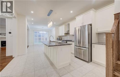 Spacious kitchen featuring an island with a built-in sink, white cabinetry, stainless steel appliances, granite countertops, and tile flooring - 52 Pointer Street, Cambridge, ON - Indoor Photo Showing Kitchen With Upgraded Kitchen