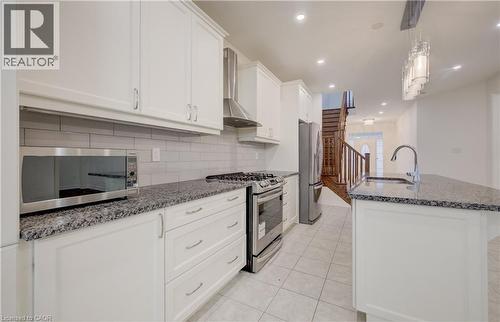 Kitchen featuring white shaker-style cabinetry, granite countertops, subway tile backsplash, stainless steel appliances, and tile flooring - 52 Pointer Street, Cambridge, ON - Indoor Photo Showing Kitchen With Upgraded Kitchen