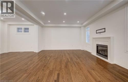 Expansive room featuring rich wood-finish flooring, a contemporary fireplace with a classic mantel, recessed ceiling lighting, and plantation shutters - 52 Pointer Street, Cambridge, ON - Indoor With Fireplace