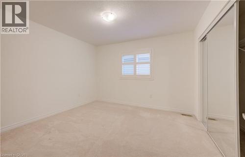 Spacious room with plush carpet, a window featuring white plantation shutters, and a wall-length mirrored closet - 52 Pointer Street, Cambridge, ON - Indoor Photo Showing Other Room