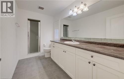 Bathroom featuring a long vanity with dual under-mount sinks, a dark stone countertop, and extensive white cabinetry - 52 Pointer Street, Cambridge, ON - Indoor Photo Showing Bathroom