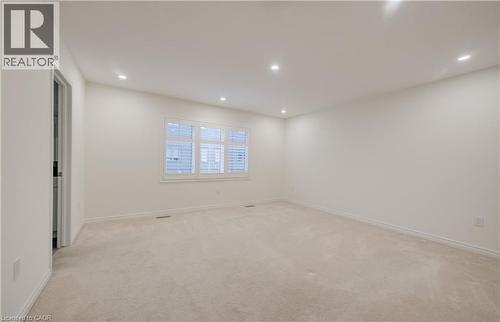 Spacious room featuring neutral carpeting, white walls, recessed ceiling lighting, and a multi-pane window with white plantation shutters - 52 Pointer Street, Cambridge, ON - Indoor Photo Showing Other Room
