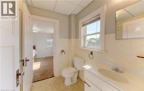 Bathroom featuring a single window, a white vanity with an integrated sink, a toilet, patterned wall tile, and a mirrored medicine cabinet - 224 Weber Street E, Kitchener, ON - Indoor Photo Showing Bathroom