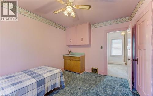 Room featuring blue carpeting, a ceiling fan with integrated lighting, and a built-in wet bar with wood cabinetry, a sink, and upper cabinets - 224 Weber Street E, Kitchener, ON - Indoor Photo Showing Bedroom