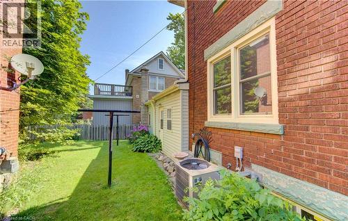 Green lawn area bordered by a red brick exterior with a window featuring light-colored trim and a decorative sill - 224 Weber Street E, Kitchener, ON - Outdoor With Exterior