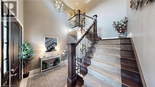 Grand foyer featuring a dark wood front door with sidelights, a double-height ceiling, and a prominent staircase with dark wood treads, light-toned carpet runner, and wrought iron balusters - 537 Millstream Drive, Waterloo, ON - Indoor Photo Showing Other Room