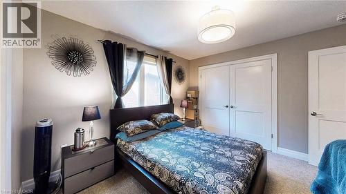 Bright bedroom featuring light gray walls, plush carpet flooring, a multi-panel window with curtains, a built-in double-door closet, and a contemporary ceiling light fixture - 537 Millstream Drive, Waterloo, ON - Indoor Photo Showing Bedroom