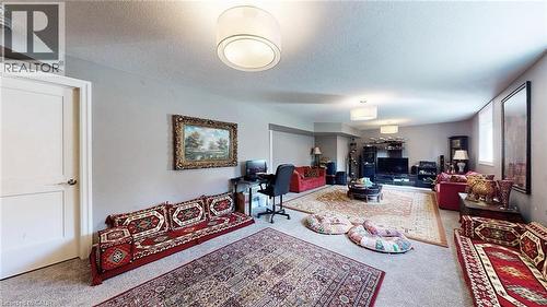 Spacious living area featuring neutral carpeting, recessed wall sections, multiple ceiling-mounted light fixtures, and a white interior door - 537 Millstream Drive, Waterloo, ON - Indoor Photo Showing Other Room