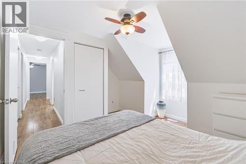 Attic bedroom featuring an angled ceiling, wood-finish flooring, a ceiling fan with integrated lighting, and a window with sheer curtains - 34 Peachtree Crescent, Cambridge, ON - Indoor Photo Showing Bedroom