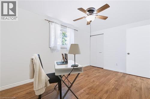 Bright room featuring wood-finish flooring, a window with white sheer curtains, a ceiling fan with integrated lighting, and white walls - 34 Peachtree Crescent, Cambridge, ON - Indoor