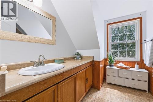 Bathroom featuring a wood vanity with an integrated sink, a rectangular mirror with a textured frame, and a window with wood trim - 34 Peachtree Crescent, Cambridge, ON - Indoor Photo Showing Bathroom