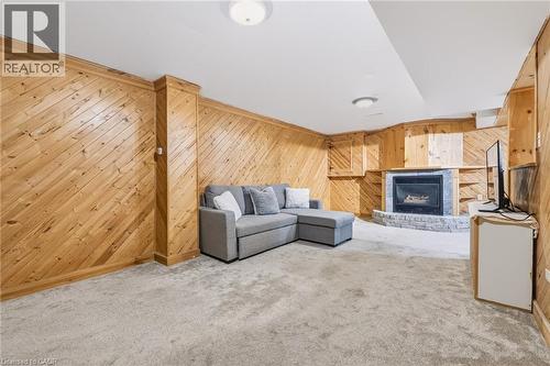 Recreational room featuring diagonal wood paneling, a built-in fireplace with stone surround, recessed shelving, and soft carpet flooring - 34 Peachtree Crescent, Cambridge, ON - Indoor With Fireplace