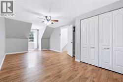 Spacious room featuring wood-finish flooring, light grey walls, and a multi-pane window - 