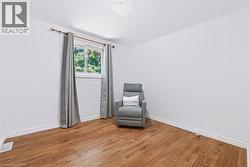 Bright room featuring wood-finish flooring, white baseboards, a single window, and a flush-mount ceiling light - 