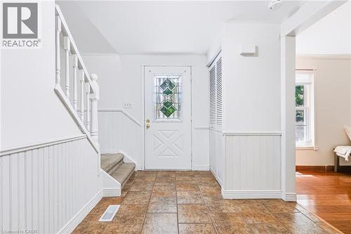 Foyer featuring tile flooring, white wainscoting, a staircase with carpeting on treads, a front door with decorative glass inserts, and louvered closet doors - 34 Peachtree Crescent, Cambridge, ON - Indoor Photo Showing Other Room