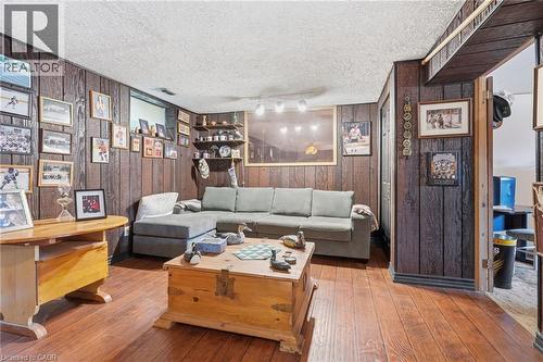 Recreation room featuring wood-finish flooring, dark wood paneling, a built-in shelving unit, and track lighting - 46 Brett Court, Hamilton, ON - Indoor Photo Showing Living Room