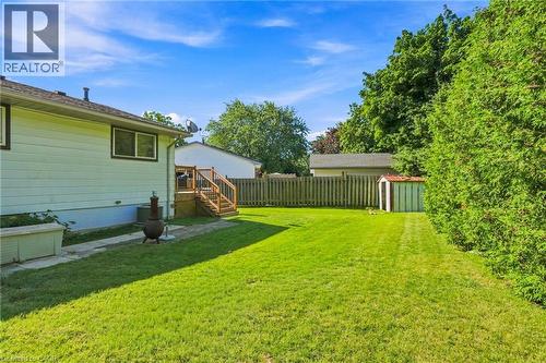Expansive grassy yard featuring a wooden deck with railing and stairs, a privacy fence, mature trees, and a storage shed - 46 Brett Court, Hamilton, ON - Outdoor