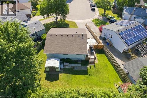 Expansive backyard featuring a manicured lawn, an outdoor deck with patio umbrella, a detached storage shed, mature perimeter trees, and a privacy fence - 46 Brett Court, Hamilton, ON - Outdoor
