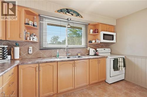 Kitchen featuring wood-finish cabinetry, a double basin stainless steel sink, and a tile backsplash - 46 Brett Court, Hamilton, ON - Indoor Photo Showing Kitchen With Double Sink