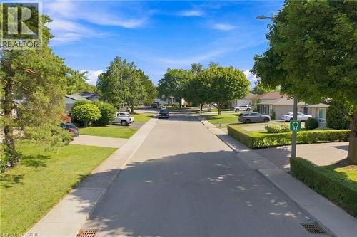 Residential streetscape featuring a paved road, concrete sidewalks, and manicured lawns - 46 Brett Court, Hamilton, ON - Outdoor With View