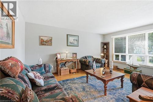 Living area featuring light gray wall paint, wood-finish flooring, and a large window with white blinds - 46 Brett Court, Hamilton, ON - Indoor Photo Showing Living Room