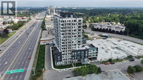 Modern high-rise residential building featuring a multi-story facade, extensive window arrays, and a ground-level parking area - 1333 Weber Street E Unit# 708, Kitchener, ON - Outdoor With View