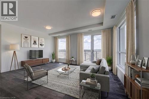 Spacious living area featuring dark wood-finish flooring, a wall of windows, and a glass-paneled door opening to an outdoor area - 1333 Weber Street E Unit# 708, Kitchener, ON - Indoor Photo Showing Living Room