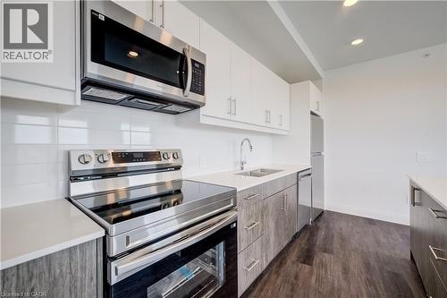 Contemporary kitchen featuring stainless steel appliances, white subway tile backsplash, and light-toned wood-finish lower cabinetry - 1333 Weber Street E Unit# 708, Kitchener, ON - Indoor Photo Showing Kitchen With Stainless Steel Kitchen With Upgraded Kitchen