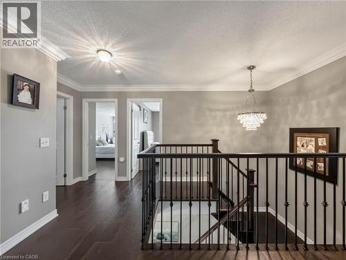 Elegant upper-level hallway featuring dark wood-finish flooring, soft gray walls, and black metal stair railings with vertical balusters - 80 Sutherland Crescent, Ancaster, ON - Indoor Photo Showing Other Room