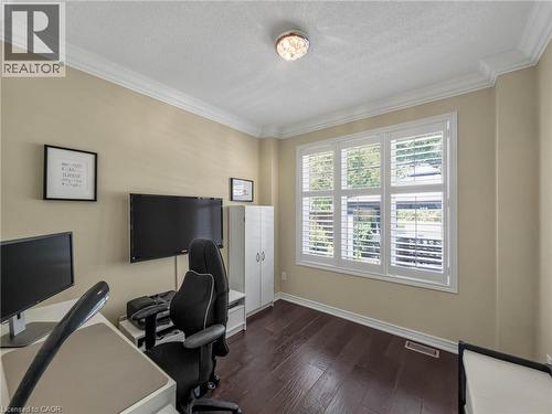 Dedicated home office featuring dual monitor setup with dark wood-finish flooring, soft yellow wall finishes, and abundant natural light from multi-pane windows with plantation shutters - 80 Sutherland Crescent, Ancaster, ON - Indoor Photo Showing Office