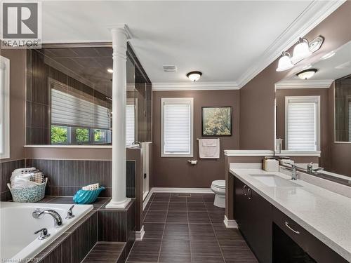 Spa-inspired primary bathroom featuring dual vanities with quartz countertops, an enclosed glass-enclosed shower with tile surround, soaking tub, dark tile flooring, and abundant natural light from mu - 80 Sutherland Crescent, Ancaster, ON - Indoor Photo Showing Bathroom