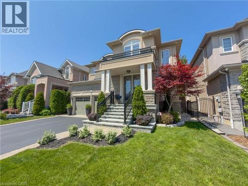 Stately facade featuring a stone and stucco exterior, prominent front porch with columns, wrought iron railings, and an integrated garage - 80 Sutherland Crescent, Ancaster, ON - Outdoor With Facade