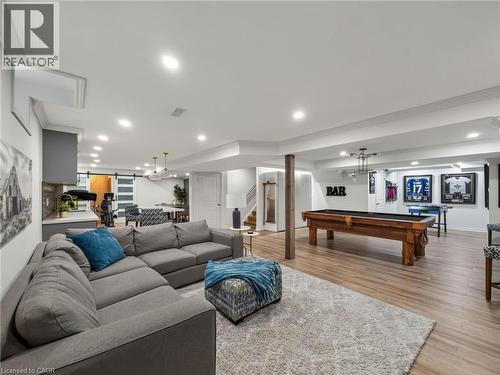 Expansive lower-level recreation space featuring a sectional seating arrangement, wood-finish flooring throughout, recessed ceiling lighting, and a billiards table - 80 Sutherland Crescent, Ancaster, ON - Indoor Photo Showing Living Room