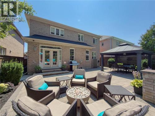 Paved patio area featuring a stone fire pit, a covered outdoor dining space, and direct access to the interior via French doors - 80 Sutherland Crescent, Ancaster, ON - Outdoor With Deck Patio Veranda