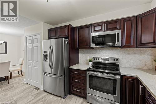 Kitchen featuring rich wood cabinetry, stainless steel appliances, light-toned countertops, and a patterned tile backsplash - 167 Berkindale Drive, Hamilton, ON - Indoor Photo Showing Kitchen