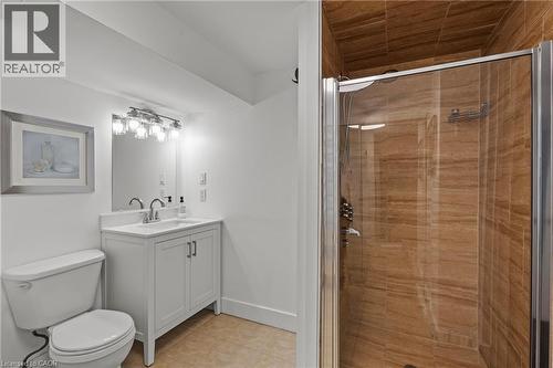 Bathroom featuring a glass-enclosed shower with horizontally-stacked brown tile, a white vanity with a rectangular sink, a polished chrome faucet, and a wall-mounted light fixture - 167 Berkindale Drive, Hamilton, ON - Indoor Photo Showing Bathroom