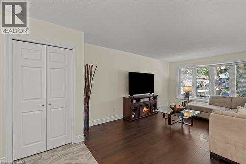 Living area featuring dark wood-finish flooring and a wide bay window with blinds - 167 Berkindale Drive, Hamilton, ON - Indoor Photo Showing Living Room