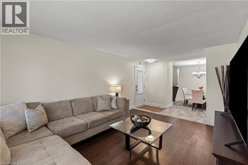Living area featuring wood-finish flooring, a neutral wall palette, and an open entryway to a dining space - 167 Berkindale Drive, Hamilton, ON - Indoor Photo Showing Living Room