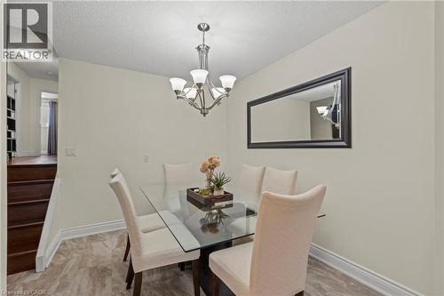 Elegant dining room featuring a glass-top table with dark wood base, paired with upholstered dining chairs in neutral tones - 167 Berkindale Drive, Hamilton, ON - Indoor Photo Showing Dining Room