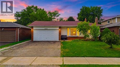 Charming single-story home featuring a white garage door, brick exterior accents, and welcoming front entrance with illuminated fixtures - 6346 Neuchatel Road, Mississauga, ON - Outdoor