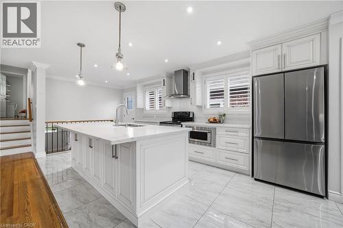 Sophisticated kitchen featuring white shaker cabinetry, a large waterfall-edge island with seating, stainless steel appliances including a French-door refrigerator and pendant lighting, marble-finish - 6346 Neuchatel Road, Mississauga, ON - Indoor Photo Showing Kitchen With Upgraded Kitchen