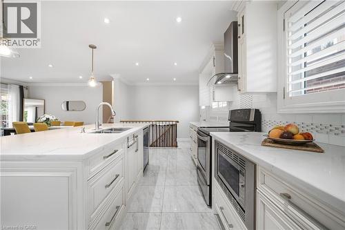 Sophisticated kitchen featuring white cabinetry with brushed metal hardware, white quartz countertops, and stainless steel appliances including a gas cooktop and built-in microwave - 6346 Neuchatel Road, Mississauga, ON - Indoor Photo Showing Kitchen With Double Sink With Upgraded Kitchen