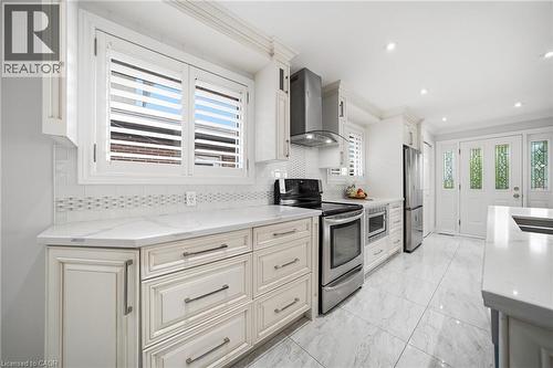 Gourmet kitchen featuring custom cabinetry with brushed metal hardware, quartz countertops, subway tile backsplash, and stainless steel appliances including a gas range, built-in refrigerator, and dis - 6346 Neuchatel Road, Mississauga, ON - Indoor Photo Showing Kitchen