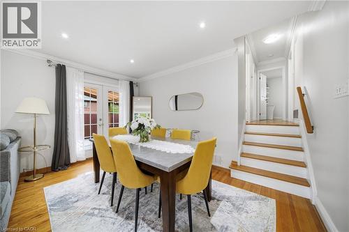 Elegant dining room showcasing warm wood-finish flooring, a wood dining table with black legs, and four upholstered yellow chairs - 6346 Neuchatel Road, Mississauga, ON - Indoor Photo Showing Dining Room