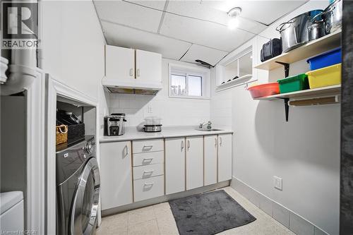 Dedicated laundry room featuring front-load washer, ample cabinetry with multiple drawers, stainless steel countertop, open shelving with organized storage bins, and practical layout designed for effi - 6346 Neuchatel Road, Mississauga, ON - Indoor Photo Showing Laundry Room