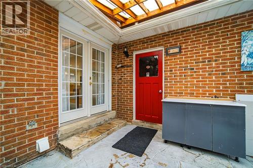 Brick exterior patio featuring a red entry door, white French doors, and an overhead pergola - 6346 Neuchatel Road, Mississauga, ON - Outdoor With Exterior