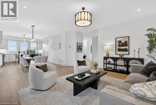 Open-concept living area featuring a wood-finish plank floor, recessed ceiling lighting, and a black metal coffee table anchoring the seating zone - 100 Watershore Drive Unit# 15, Hamilton, ON - Indoor Photo Showing Living Room