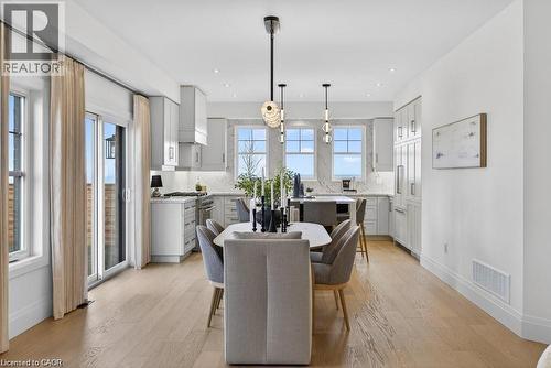 Open-concept living space featuring wood-finish flooring, a modern kitchen with light cabinetry, stainless steel appliances, and a built-in refrigerator - 100 Watershore Drive Unit# 15, Hamilton, ON - Indoor Photo Showing Dining Room
